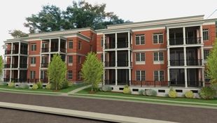 Twin brick multi-family, 4 story buildings alongside a manicured street and greenspace.
