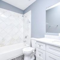 Guest bathroom with tub shower and white vanity.