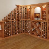 Corner wine rack filled with wine, decanter, a moniter, and flowers