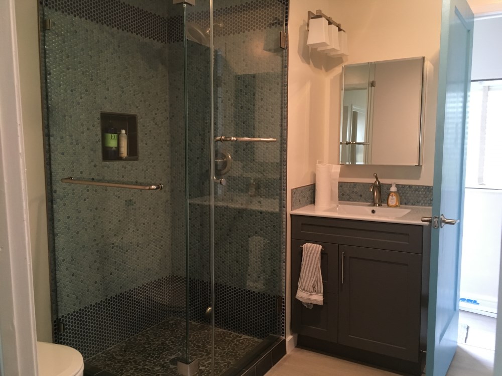 Remodeled bathroom with glass shower and vanity.
